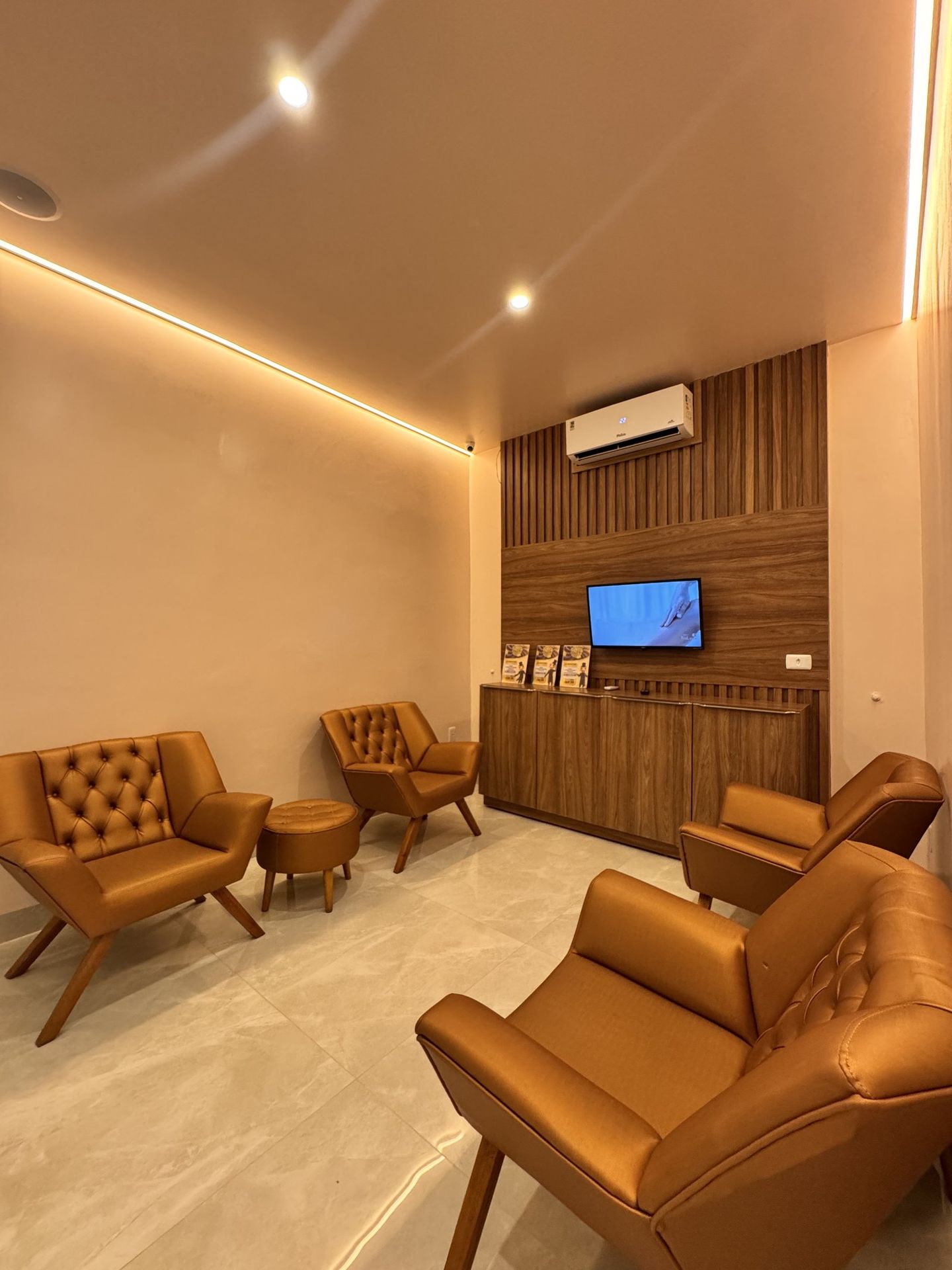 Sala de espera com poltronas caramelo e painel ripado de madeira